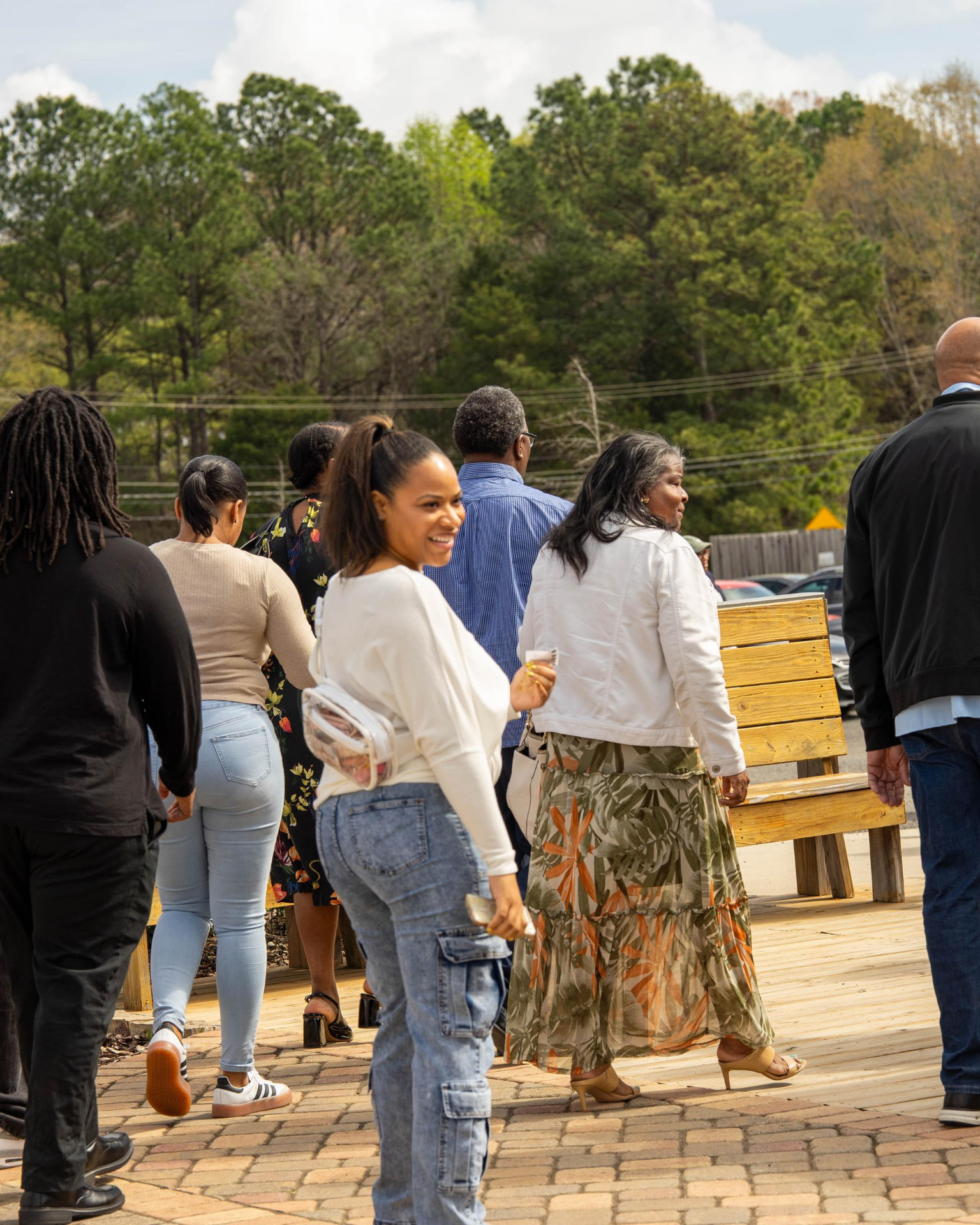 Adults walking together along an outdoor patio beside wooden benches.