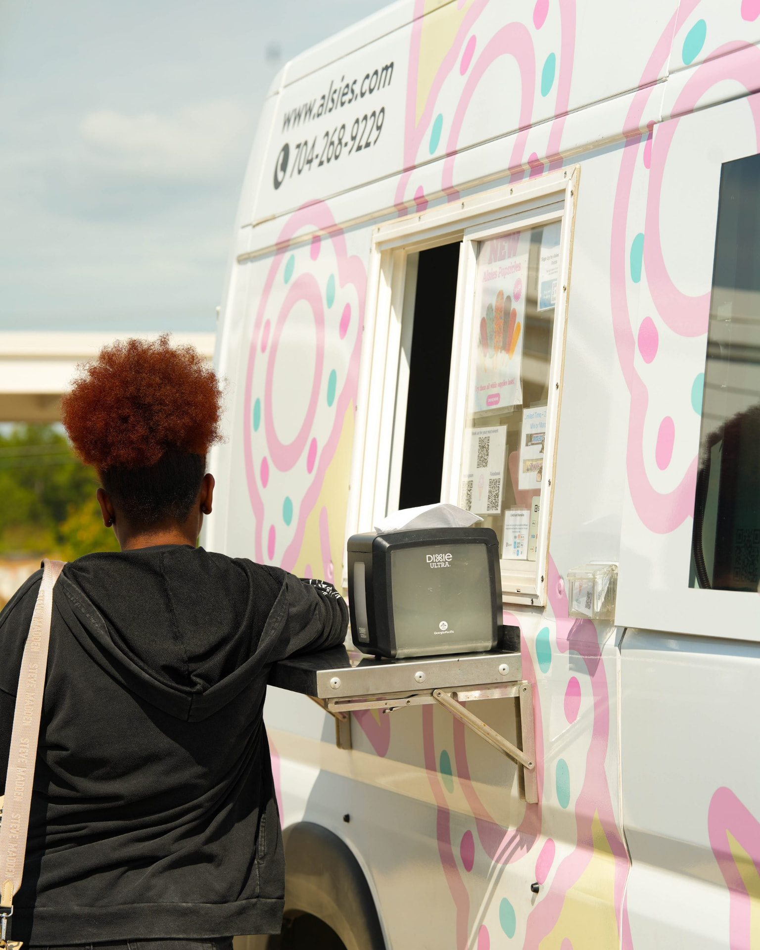 A person standing at the serving window of a colorful food truck.