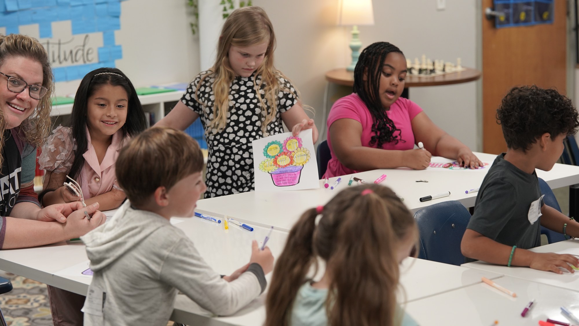 A mentor and children coloring together at a craft table