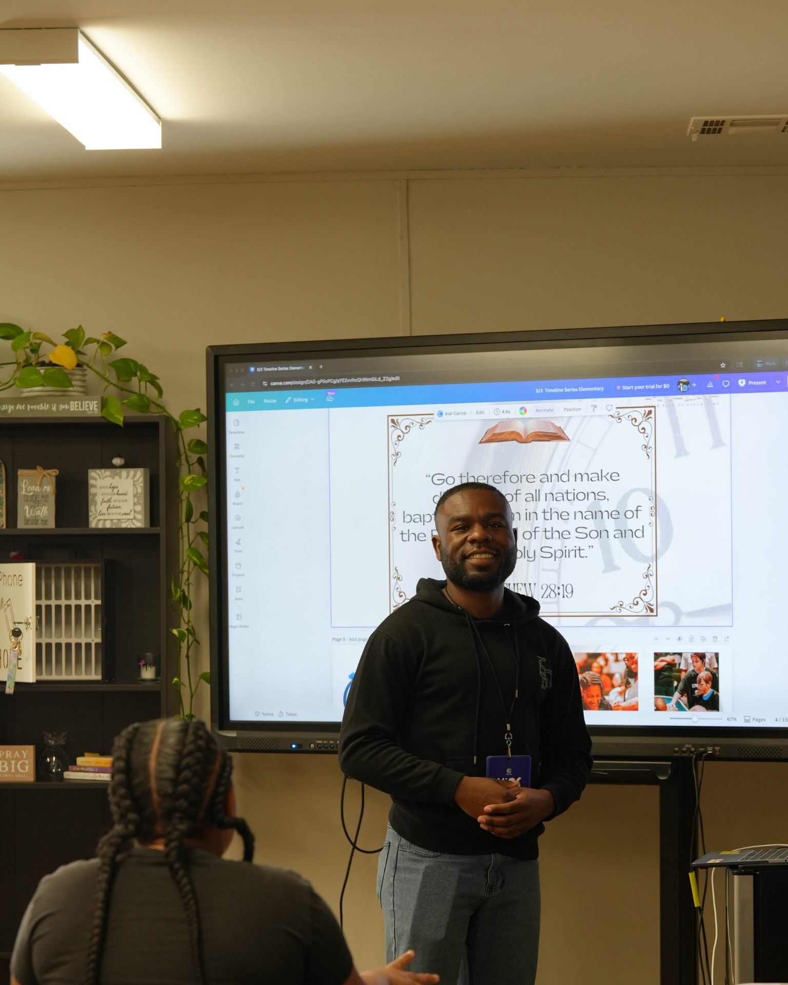 A man standing and smiling in front of a large presentation screen.